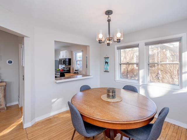 dining space with an inviting chandelier and light hardwood / wood-style flooring