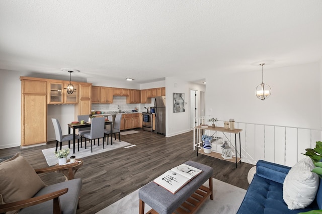 living room featuring dark wood-type flooring, sink, a textured ceiling, and an inviting chandelier