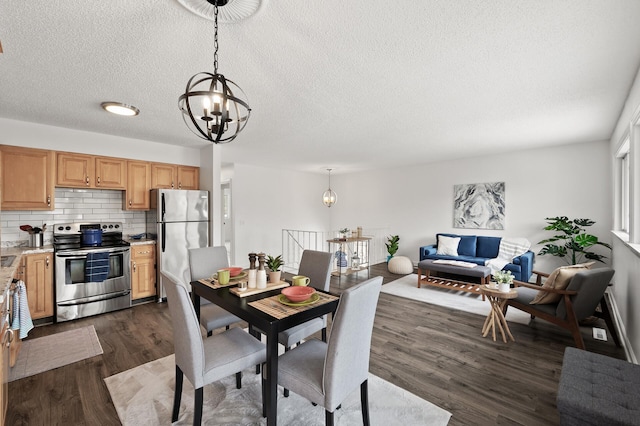 dining space with dark wood-type flooring, a textured ceiling, and an inviting chandelier