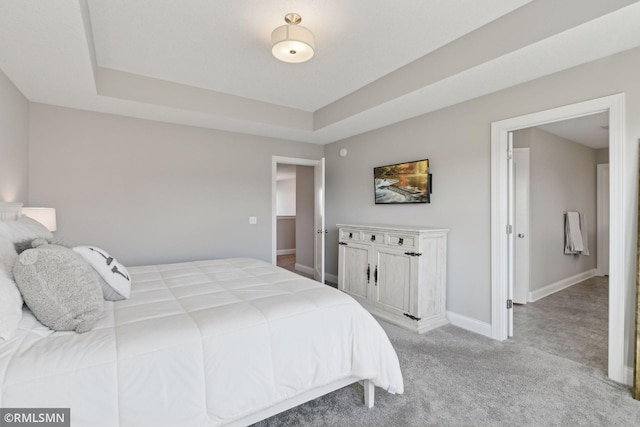 bedroom featuring a raised ceiling, light colored carpet, and baseboards