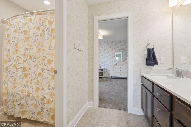 bathroom with wallpapered walls, baseboards, and vanity