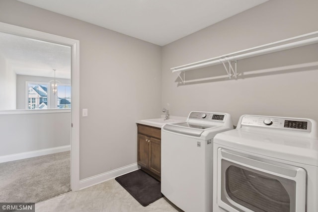 laundry area featuring sink, cabinets, a notable chandelier, light colored carpet, and washer and clothes dryer