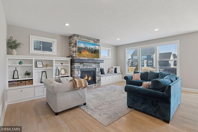 living room featuring a textured ceiling, a fireplace, and light hardwood / wood-style flooring