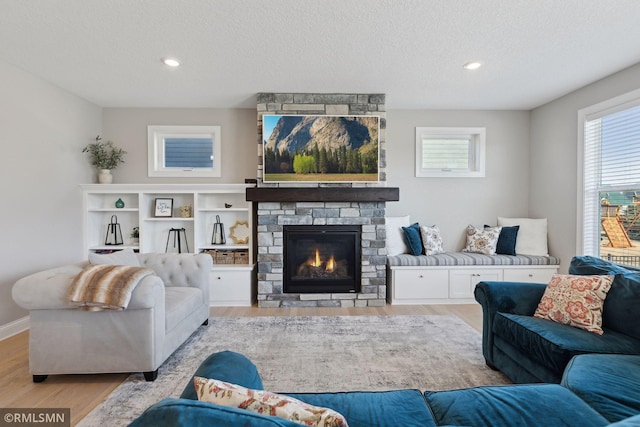 living room featuring a textured ceiling, light hardwood / wood-style floors, and a fireplace