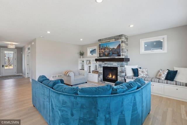 living room with a stone fireplace and light wood-type flooring