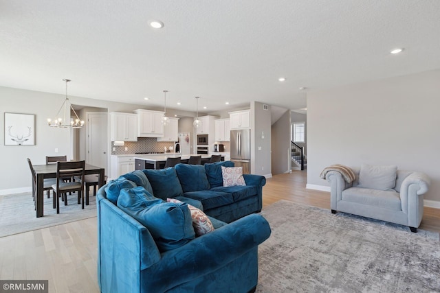 living room featuring a textured ceiling, an inviting chandelier, and light hardwood / wood-style flooring