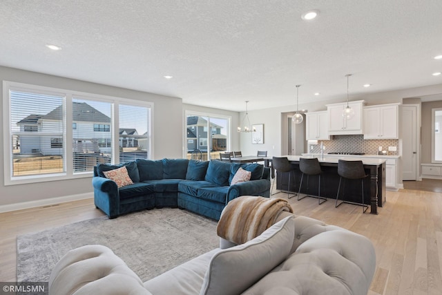 living room with an inviting chandelier, light hardwood / wood-style flooring, and a textured ceiling