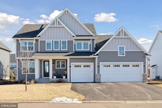 craftsman inspired home with roof with shingles, an attached garage, board and batten siding, stone siding, and driveway