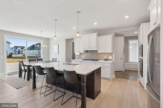 kitchen featuring appliances with stainless steel finishes, light countertops, white cabinetry, and a sink