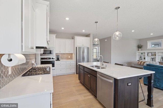 kitchen with white cabinetry, a kitchen island with sink, appliances with stainless steel finishes, and a sink