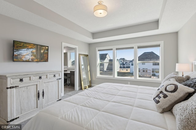 bedroom featuring a raised ceiling, a textured ceiling, and ensuite bathroom