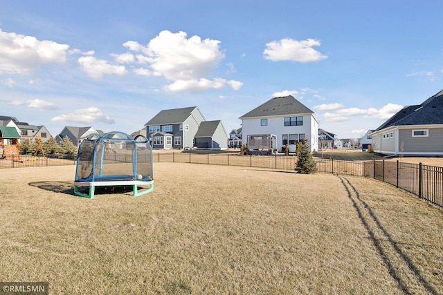 view of jungle gym featuring a trampoline, a residential view, and a yard