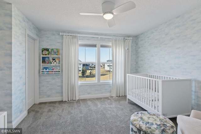 bedroom featuring a textured ceiling, carpet floors, a ceiling fan, baseboards, and wallpapered walls