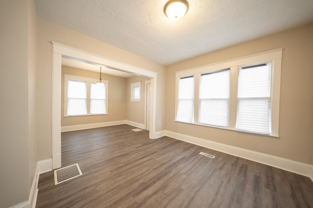 empty room featuring dark wood-type flooring and a textured ceiling