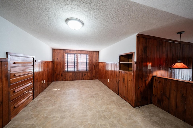 interior space with a textured ceiling and wood walls