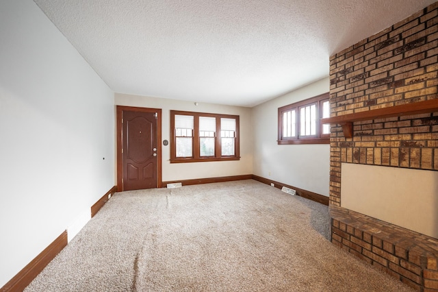 unfurnished living room featuring carpet and a textured ceiling