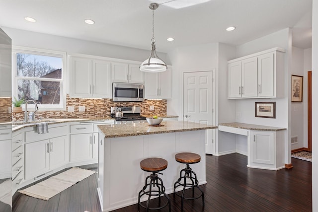 2536 Saunders Lake Dr, Minnetrista, MN 55364 - kitchen with stainless steel appliances, decorative backsplash, a center island, dark wood-style flooring, and white cabinets