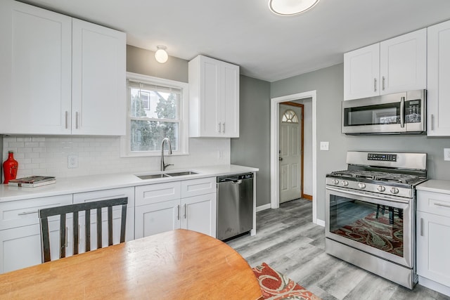 kitchen featuring white cabinetry, appliances with stainless steel finishes, sink, and light wood-type flooring