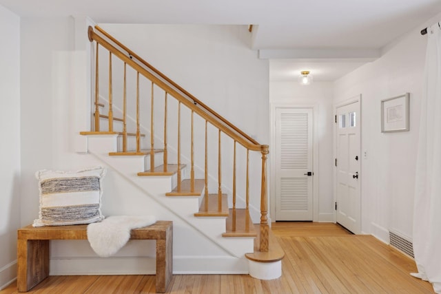 entryway with stairway, baseboards, visible vents, and wood finished floors