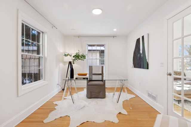 living area with plenty of natural light, visible vents, and wood finished floors