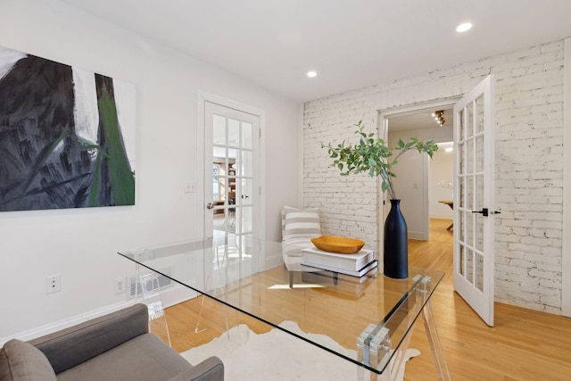 interior space with french doors, brick wall, and wood finished floors