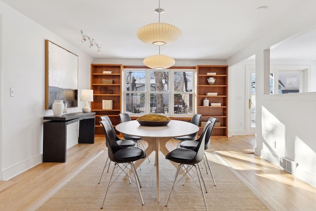 dining area featuring track lighting, baseboards, visible vents, and light wood finished floors