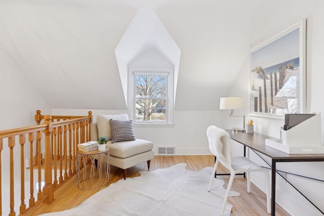 office area featuring light wood-style floors, baseboards, visible vents, and vaulted ceiling