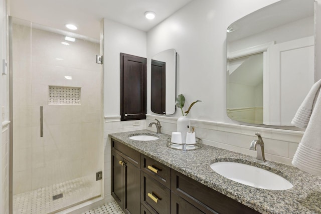 full bathroom with double vanity, a sink, tile walls, and a shower stall