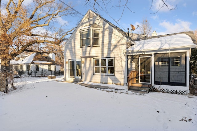 snow covered rear of property with entry steps, fence, and a chimney