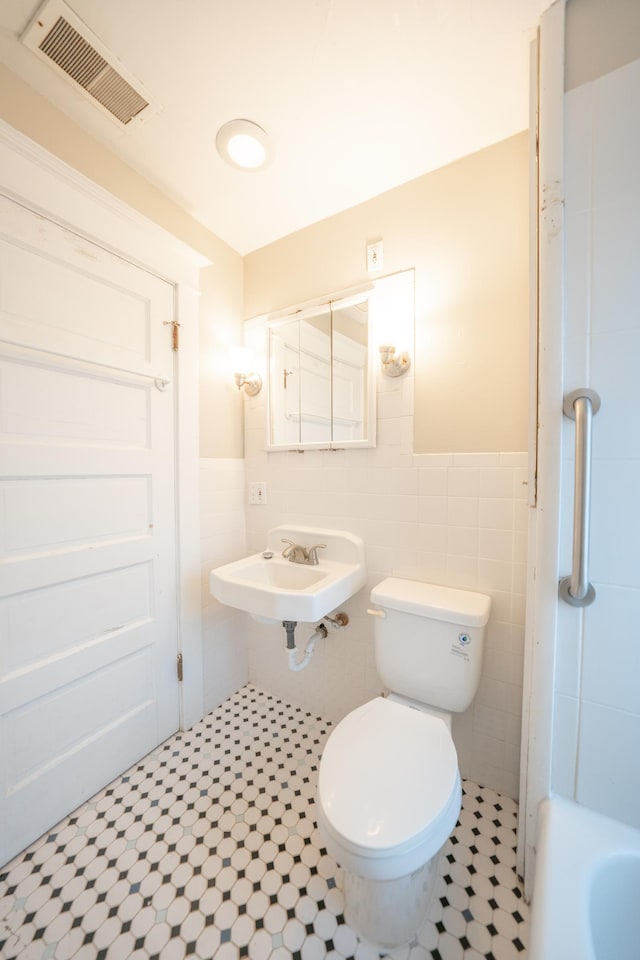 bathroom with tile walls, sink, and toilet