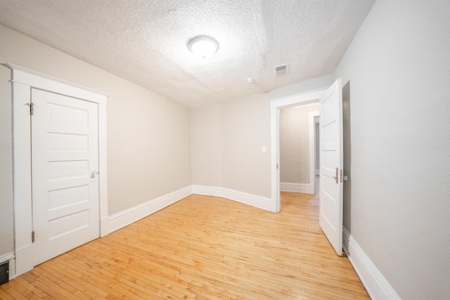 unfurnished room with light hardwood / wood-style flooring and a textured ceiling