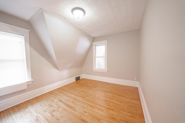 bonus room featuring hardwood / wood-style flooring, lofted ceiling, and a textured ceiling