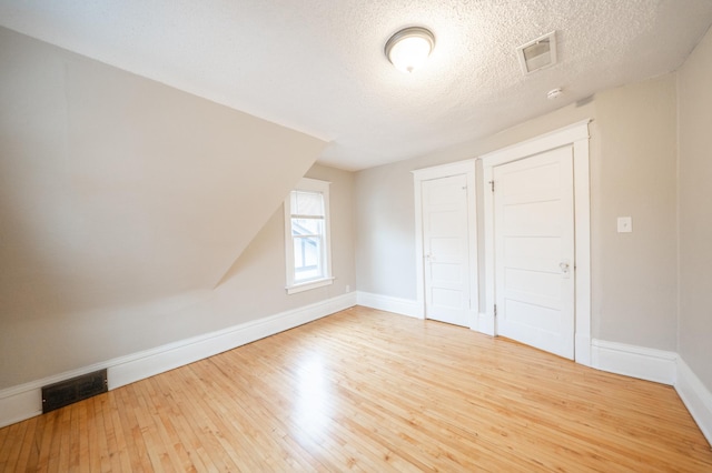 unfurnished bedroom with a textured ceiling and light wood-type flooring