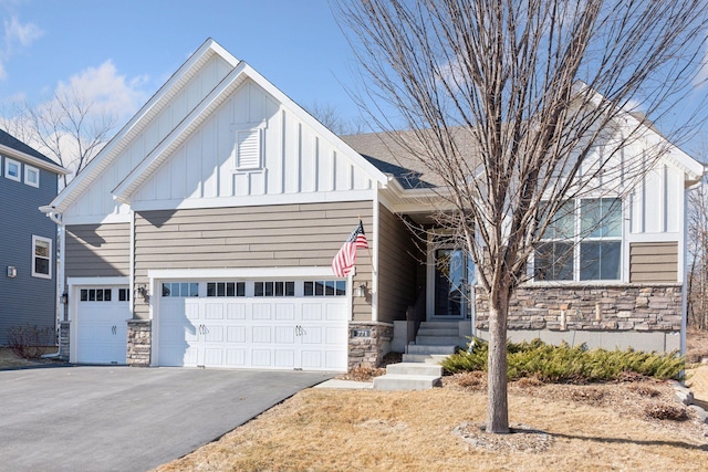 view of front of property featuring aphalt driveway, stone siding, board and batten siding, and a garage