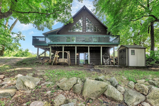 rear view of property with a wooden deck and a storage unit