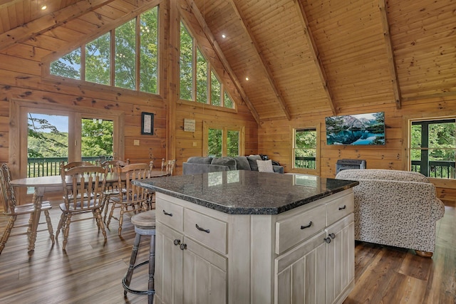 kitchen with wood walls, a center island, wooden ceiling, dark hardwood / wood-style floors, and white cabinets