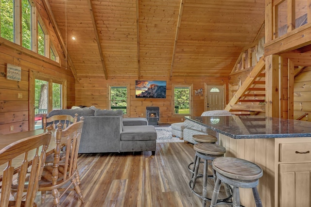 living room featuring wood walls, wood ceiling, a wood stove, hardwood / wood-style flooring, and beam ceiling