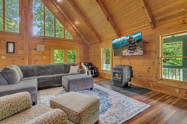 living room featuring wooden walls, beam ceiling, and a wood stove