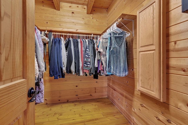 spacious closet featuring beamed ceiling and light wood-type flooring