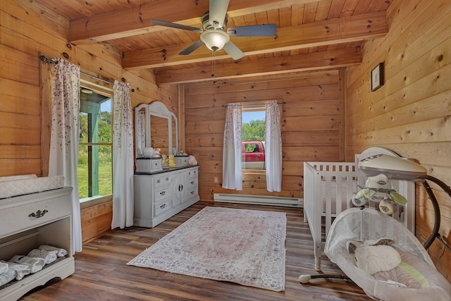 bedroom with multiple windows, wooden walls, dark hardwood / wood-style floors, and baseboard heating