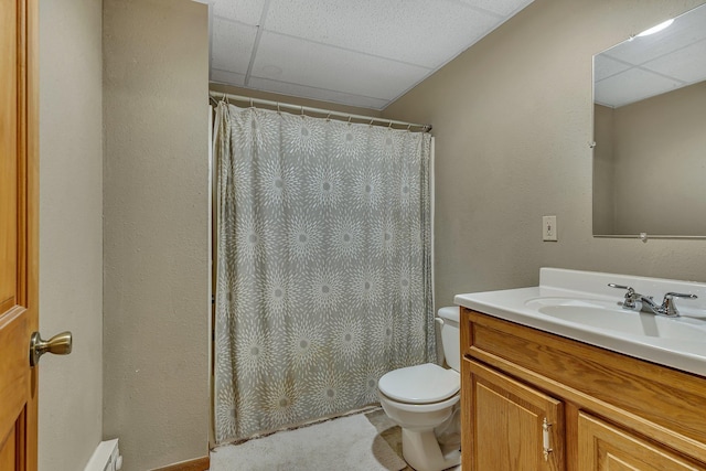 bathroom featuring vanity, toilet, and a drop ceiling