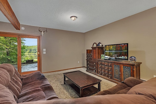 carpeted living room with beam ceiling and a textured ceiling