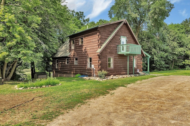 view of home's exterior with a balcony and a lawn