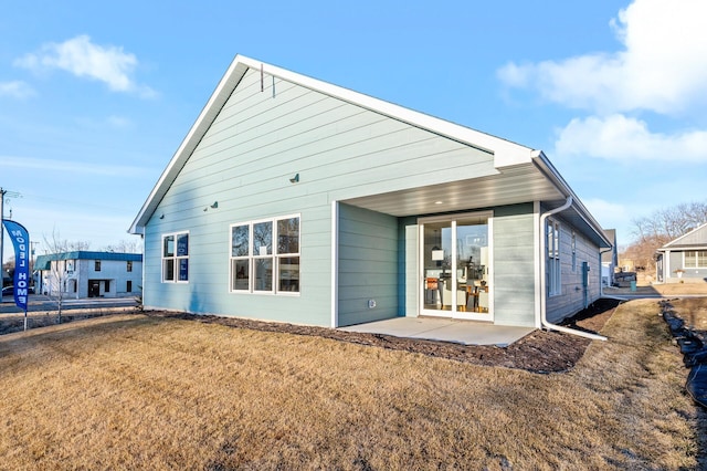 back of house with a patio and a lawn