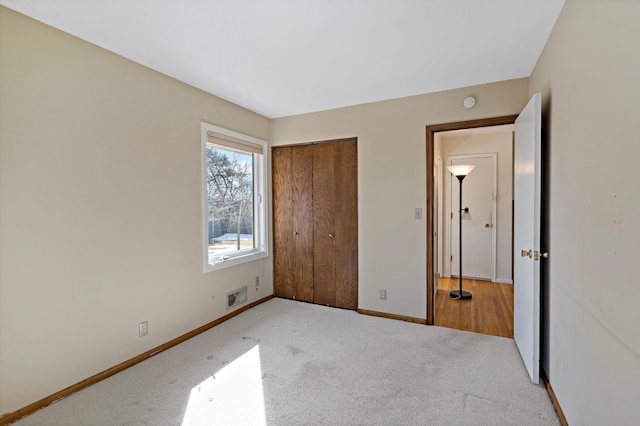 unfurnished bedroom featuring baseboards, carpet floors, a closet, and visible vents