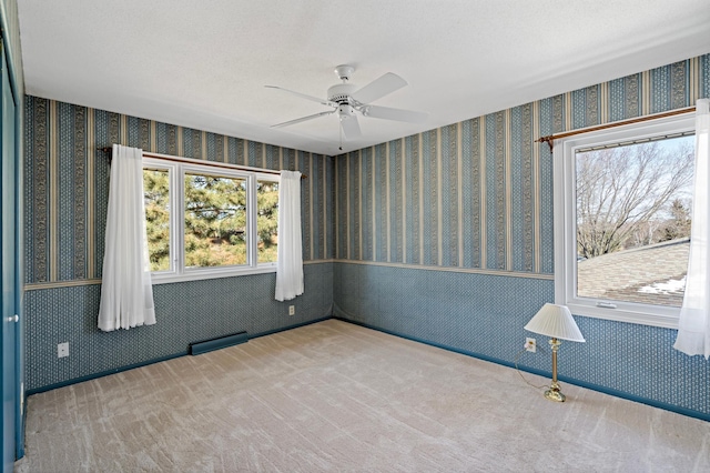 carpeted spare room featuring visible vents, a ceiling fan, and wallpapered walls