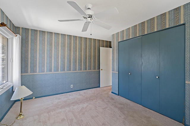 unfurnished bedroom featuring a closet, carpet flooring, wallpapered walls, and ceiling fan