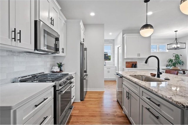 kitchen featuring sink, hanging light fixtures, white cabinets, and appliances with stainless steel finishes