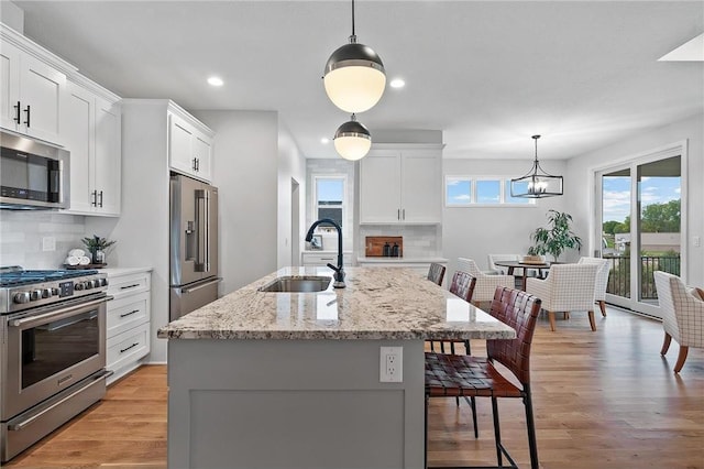 kitchen featuring stainless steel appliances, white cabinetry, hanging light fixtures, and sink