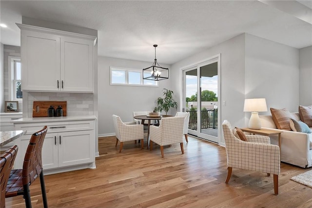 dining area with an inviting chandelier, light hardwood / wood-style flooring, and a textured ceiling